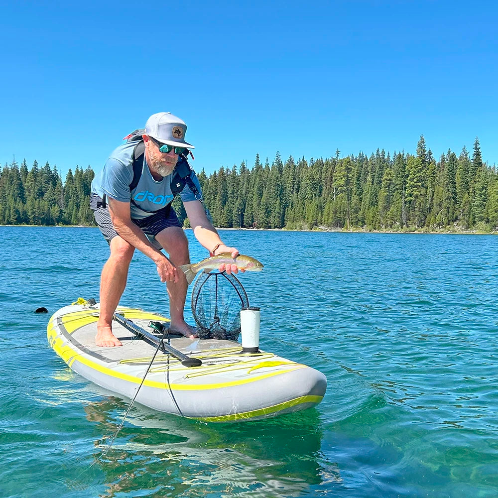 A fly fisher on a paddleboard with a TwistLock flat mount cup holder attached using adhesive and a tumbler securely attached in.