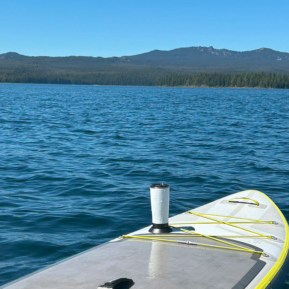 A paddleboard on a mountain lake with a TwistLock flat mount cup holder attached using adhesive and a insulated tumbler securely locked in.