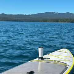 A paddleboard on a mountain lake with a TwistLock flat mount cup holder attached using adhesive and a insulated tumbler securely locked in.