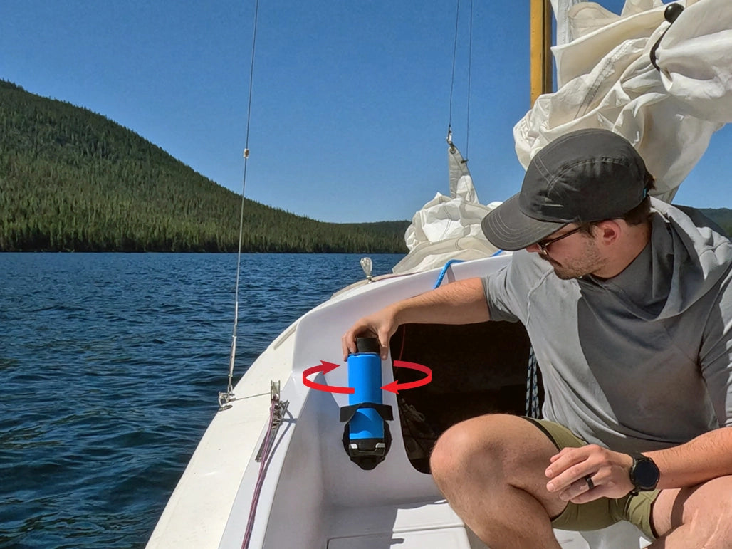 A man on a sail boat with a TwistLock Vertical Mount attachable cup holder and insulated blue canteen being locked into it. 