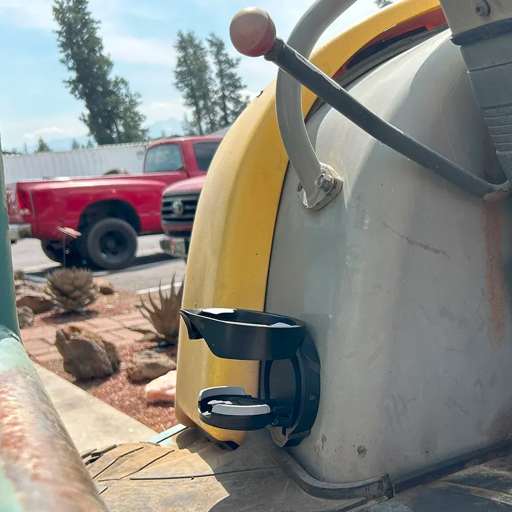 A side view of the Vertical Mount Locking Cup Holder attached to a excavator in the open position. 