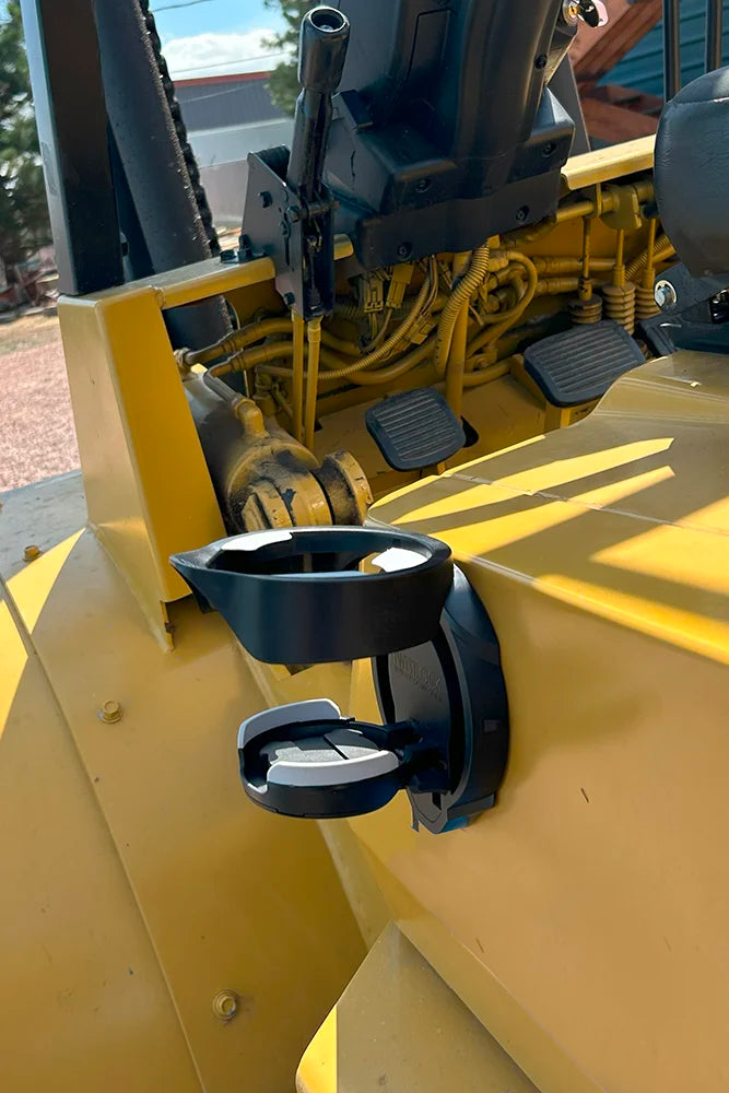A side view of the TwistLock Vertical Mount Locking Cup Holder attached to the side of an industrial forklift.