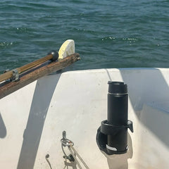 A close up of the TwistLock Vertical Mount Cup Holder attached to the transom of a small sailboat with a canteen securely locked into it.