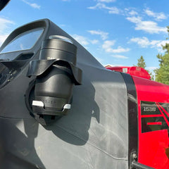 The TwistLock Vertical Mount Locking Cup Holder attached to the side of a red tractor with an insulated black can cooler securely locked in.