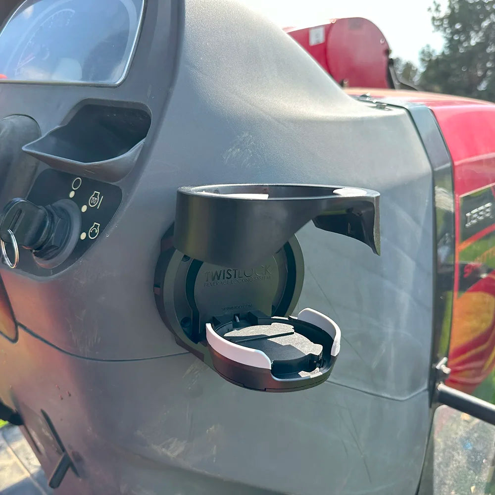 The TwistLock Vertical Mount Locking Cup Holder attached to the side of a red tractor in the open position.