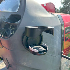 The TwistLock Vertical Mount Locking Cup Holder attached to the side of a red tractor in the open position.