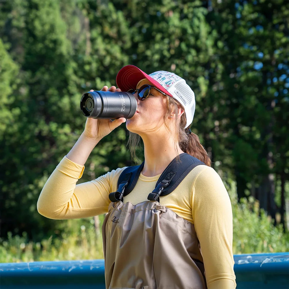 Fly fisher drinking from an insulated can cooler.